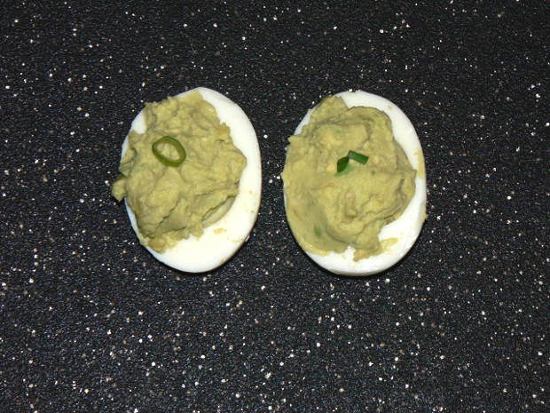 Two Avocado Deviled Eggs on a Black Cutting Board