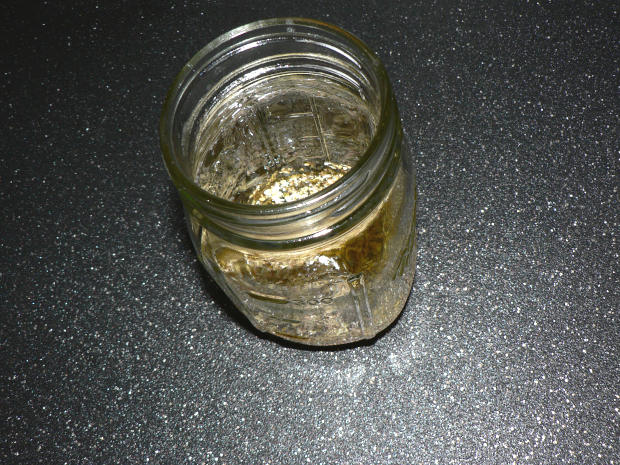 Greek Salad Dressing in a Clear Jar on a Black Surface