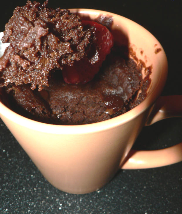 Chocolate cake in an orange mug and a piece of cake in front of it