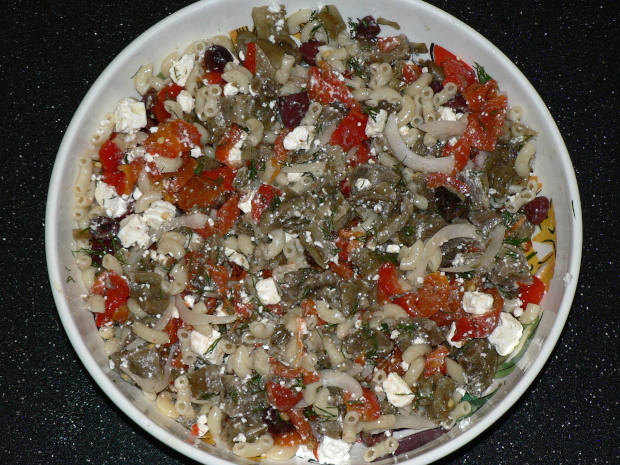 Mediterranean pasta salad in a mixing bowl