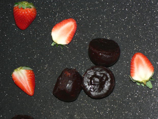 Chocolate Fudgy Brownies on a black cutting board with Strawberries