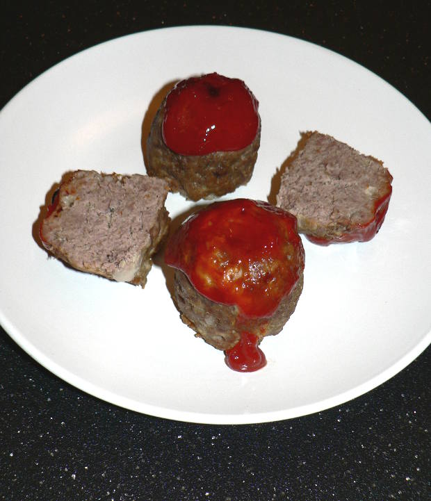 Mini meatloaves with ketchup on a white plate